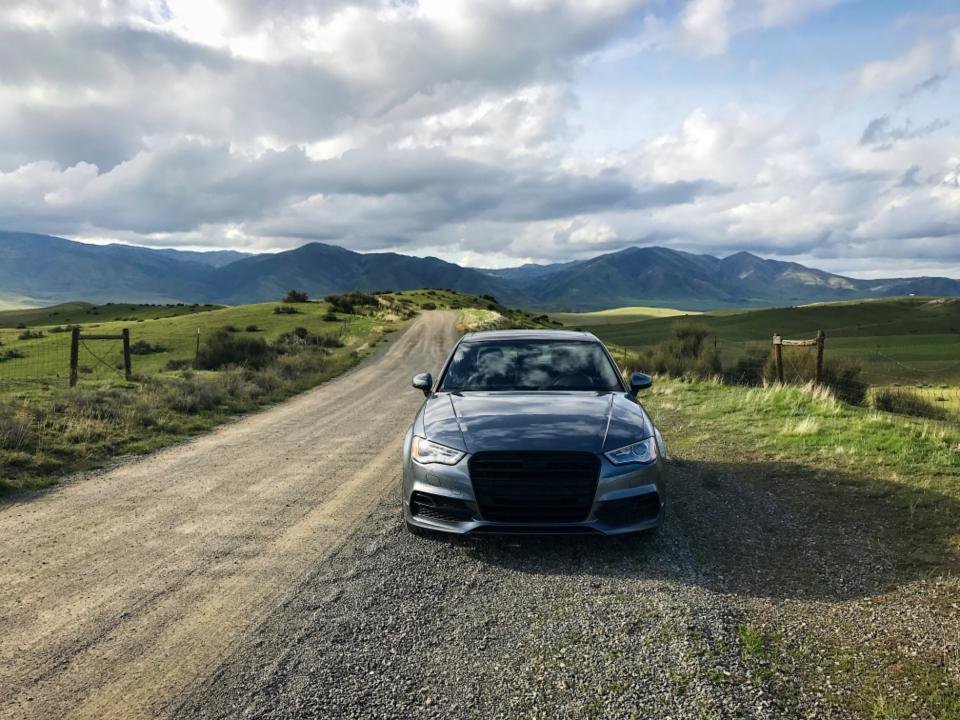 Coche aparcado en un camino de tierra con montañas al fondo