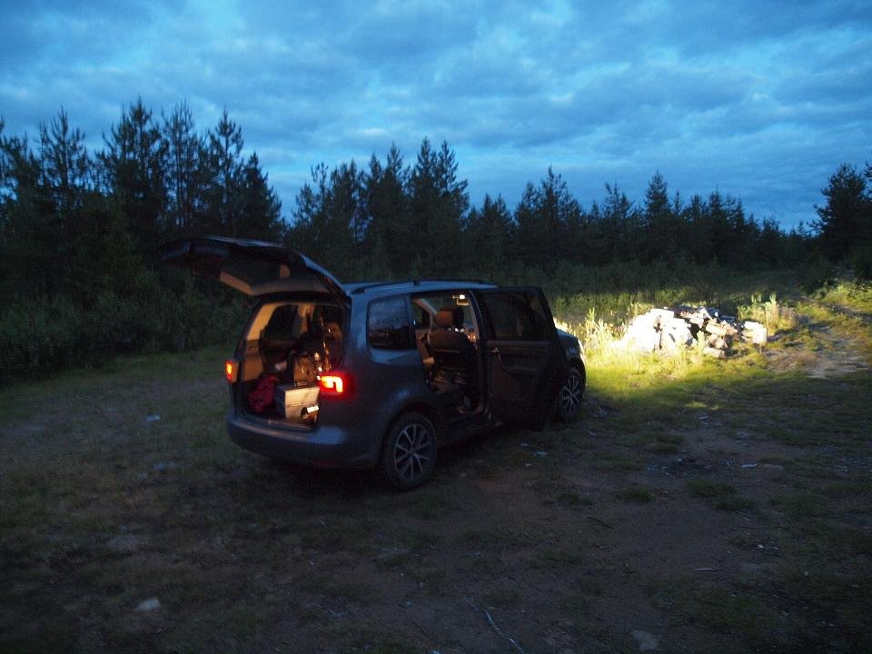 Maletero abierto de un coche con la cama preparada e iluminada por la noche